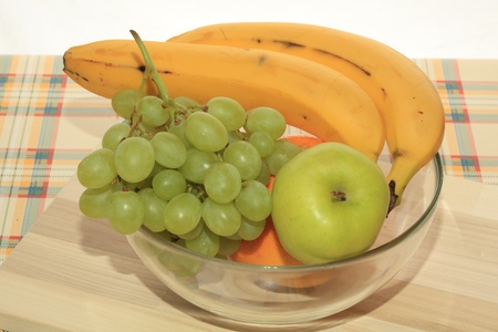 Fresh green grapes, apple, banana and grapefruit on a tableの写真素材