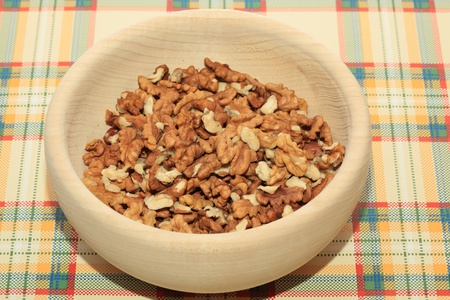 Walnuts in a wooden bowl on a tableの写真素材