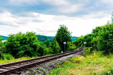 Diagonal railways between green grass. Heavy clouds on sky, beautiful nice colored image.