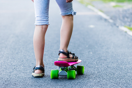 Young girl riding on skateboard on the road. Detail shot of legs, selective focus, smooth background.の写真素材