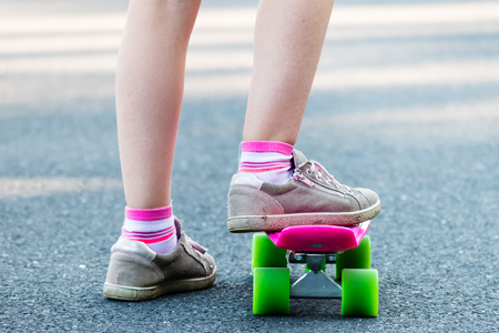 Young girl riding on skateboard on the road. Detail shot of legs, selective focus, smooth background.の写真素材