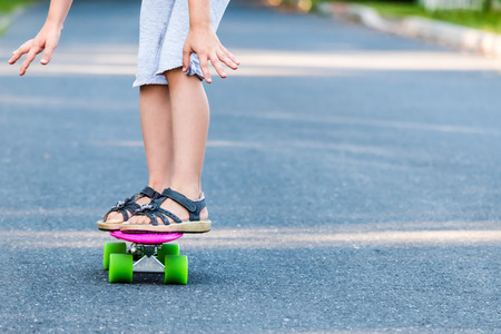 Young girl riding on skateboard on the road. Detail shot of legs, selective focus, smooth background.の写真素材