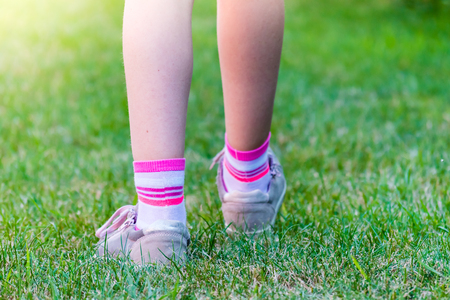 Footstep of young girl on green field of grass.  Frozen motion. Sun light on background. The view from behind.の写真素材