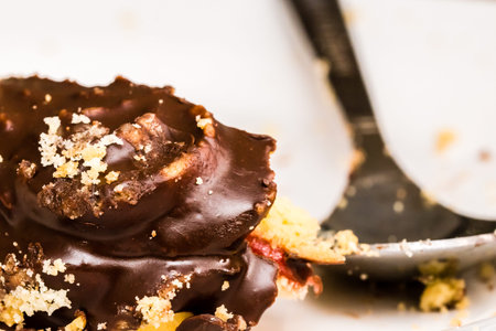 Part of small chocolate confectionery on white plate. Close-up shot, selective focus. Spoon on...