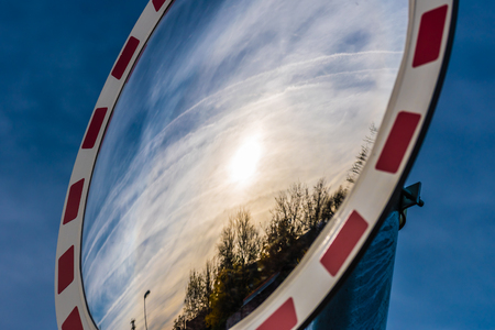 Wide angle traffic mirror on the street reflecting trees and sunset. Dark blue sky on the background.の写真素材