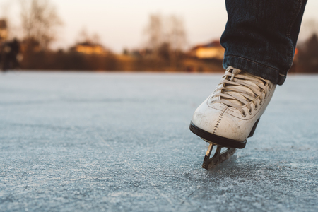 A young girl standing in skates on a frozen pond on ice. Beautiful winter day, nice blurred background.の写真素材