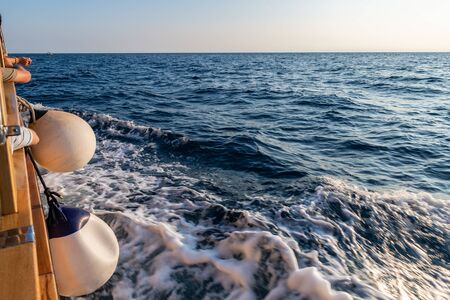 View of water and waves while sailing on the sea. Waves, part of ship and horizon.の写真素材