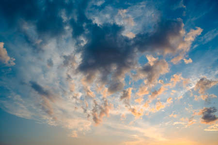 Beautiful summer sky full of clouds at sunset at golden hour. Interesting warm colors on the horizon.の写真素材