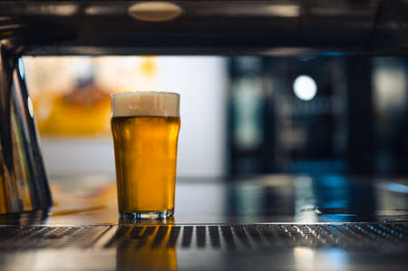 Cold beer glass on a bar or pub desk. Tasty fresh yellow beer of Czech Republic. Dark pub on background.の写真素材