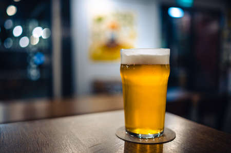 Cold beer glass on a bar or pub desk. Tasty fresh yellow beer of Czech Republic. Dark pub with nice bokeh on background.の写真素材