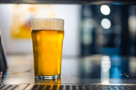 Cold beer glass on a bar or pub desk. Tasty fresh yellow beer of Czech Republic. Dark pub with nice bokeh on background.の写真素材