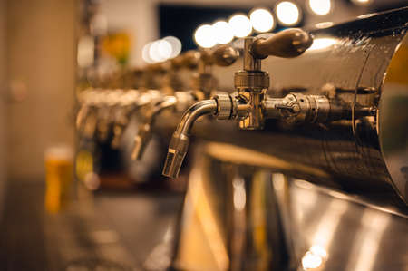 Draft beer taps in modern brewery, side view. Dark pub on a background.の写真素材