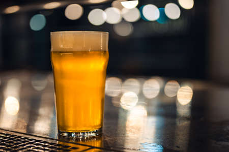 Cold beer glass on a bar or pub desk. Tasty fresh yellow beer of Czech Republic. Dark pub with nice bokeh on background.の写真素材