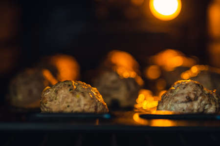 View into the oven on the baking tray for meatballs. Little light, light only from the oven. Shallow depth of field, blurred background.の写真素材