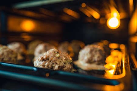 View into the oven on the baking tray for meatballs. Little light, light only from the oven. Shallow depth of field, blurred background.の写真素材