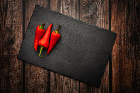Red hot chili peppers on a slate board on a dark wooden table. Top down overhead view.の写真素材