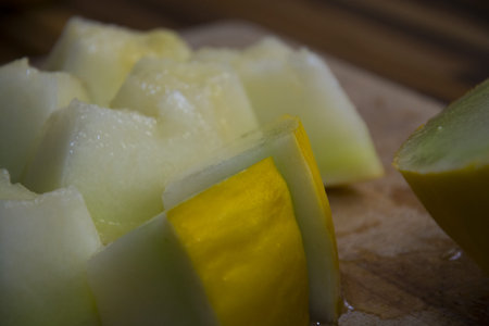 Detailed view of the pieces of the cantaloupe melon from the behind on the old wooden dick.