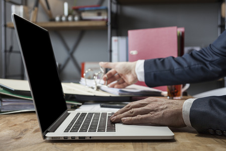 Unrecognizable man using a modern portable computer on an wooden table at homeの写真素材