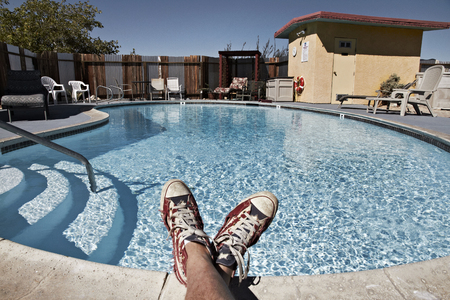 Person sitting on the edge of a swimmingpoolの写真素材
