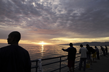 Silhouetted fishermen on Venice Pier at sunset, Californiaのeditorial素材