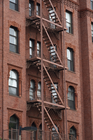 Red Fire escape stairs-downtown back alley architecture-steel and red brick backgroundの写真素材
