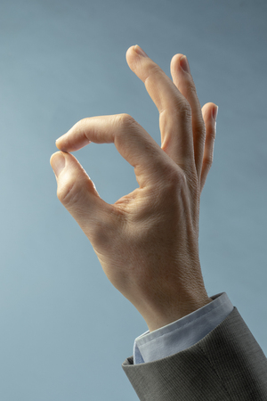 A hand of businessman in OK sign on a light blue background. Close upの写真素材
