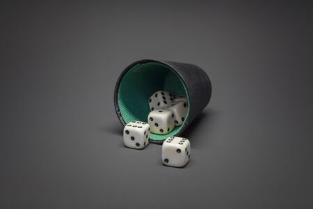 A black playing cup with several dices in the foregroundの写真素材