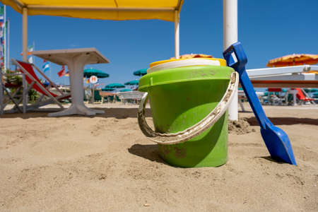 Childrens beach toys buckets, spade and shovel on sand on a sunny dayの写真素材
