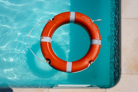 Orange lifebuoy floating on the surface of blue water in a pool