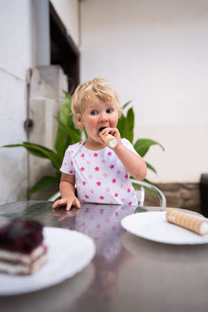 Little girl eating tube with whipped creamの写真素材