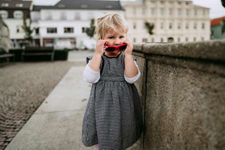 Little girl with sunglasses in cityの写真素材