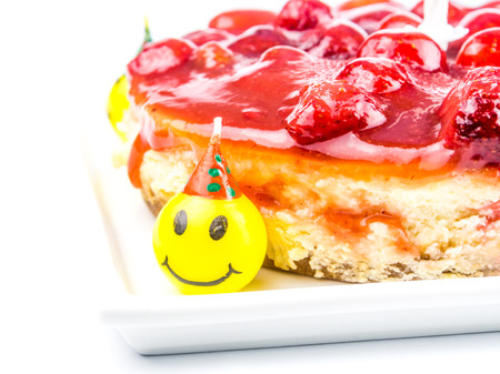 cheese cake with strawberry and funny laughing candles on white backgroundの写真素材