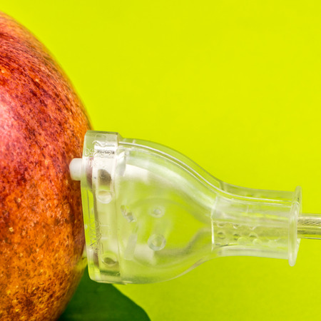 translucent plug is connected to the red apple on green background, concept of green and clean power made of biomassの写真素材