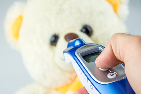 measuring temperature with tele thermometer of baby teddy bear