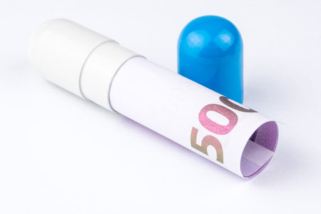 500 euro banknote is rolled into a big blue and white capsule looking like a big pill on white backgroundの写真素材