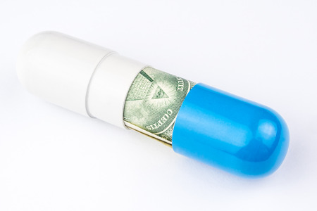 one dollar banknote is rolled into a big blue and white capsule looking like a big pill on white backgroundの写真素材