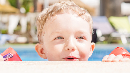 young smiling boy is swimming in a poolの写真素材