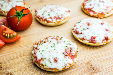 mini pizzas with ham and cheese on wooden plateの写真素材