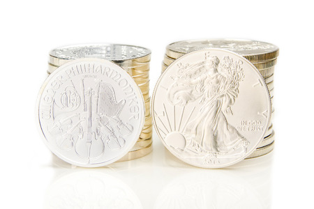 two columns of silver coins with one ounce of phillharmoniker and american eagle in front of each columnの写真素材