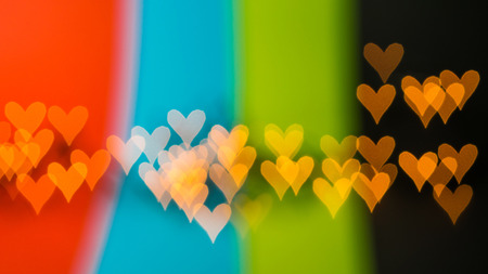 beautiful bokeh made of blurred lights in the form of hearts on multicolored backgroundの写真素材