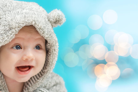adorable happy baby in bear like suit with blue background with many yellow circles