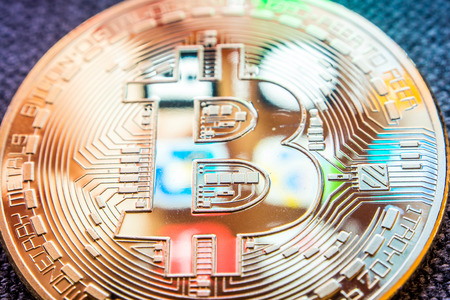 closeup of golden bitcoin coin with a smartphone display applications  reflection on its surfaceの写真素材
