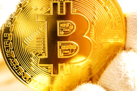 man with white gloves is holding a golden bitcoin in his hand