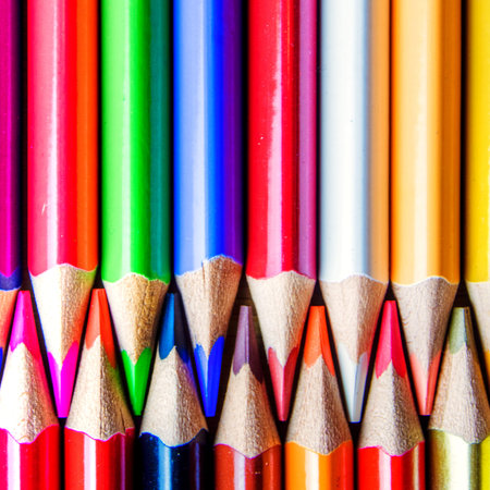 multicolored rainbow colors pencils on dirty wooden textured background forming a pattern with copy...