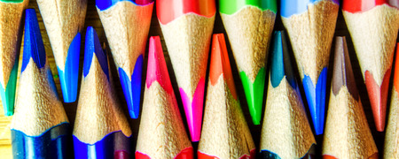 multicolored rainbow colors pencils on dirty wooden textured background forming a pattern with copy space for office, education purposeの写真素材