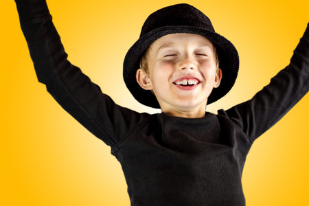 closeup of young boy in black shirt and black hat with victory, winner, yes or done it expression of his face and body gesture with free copy space for the textの写真素材