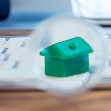 closeup of small house using a magnifier, loupe as a buying new dreamy perfect house for meの写真素材