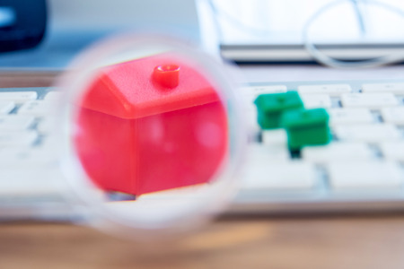 closeup of small house using a magnifier, loupe as a buying new dreamy perfect house for meの写真素材