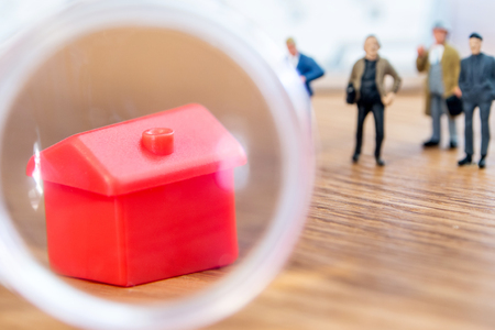 closeup of small house using a magnifier, loupe as a buying new dreamy perfect house for me with small figurines in the backgroundの写真素材