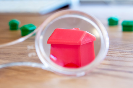 closeup of small house using a magnifier, loupe as a buying new dreamy perfect house for meの写真素材